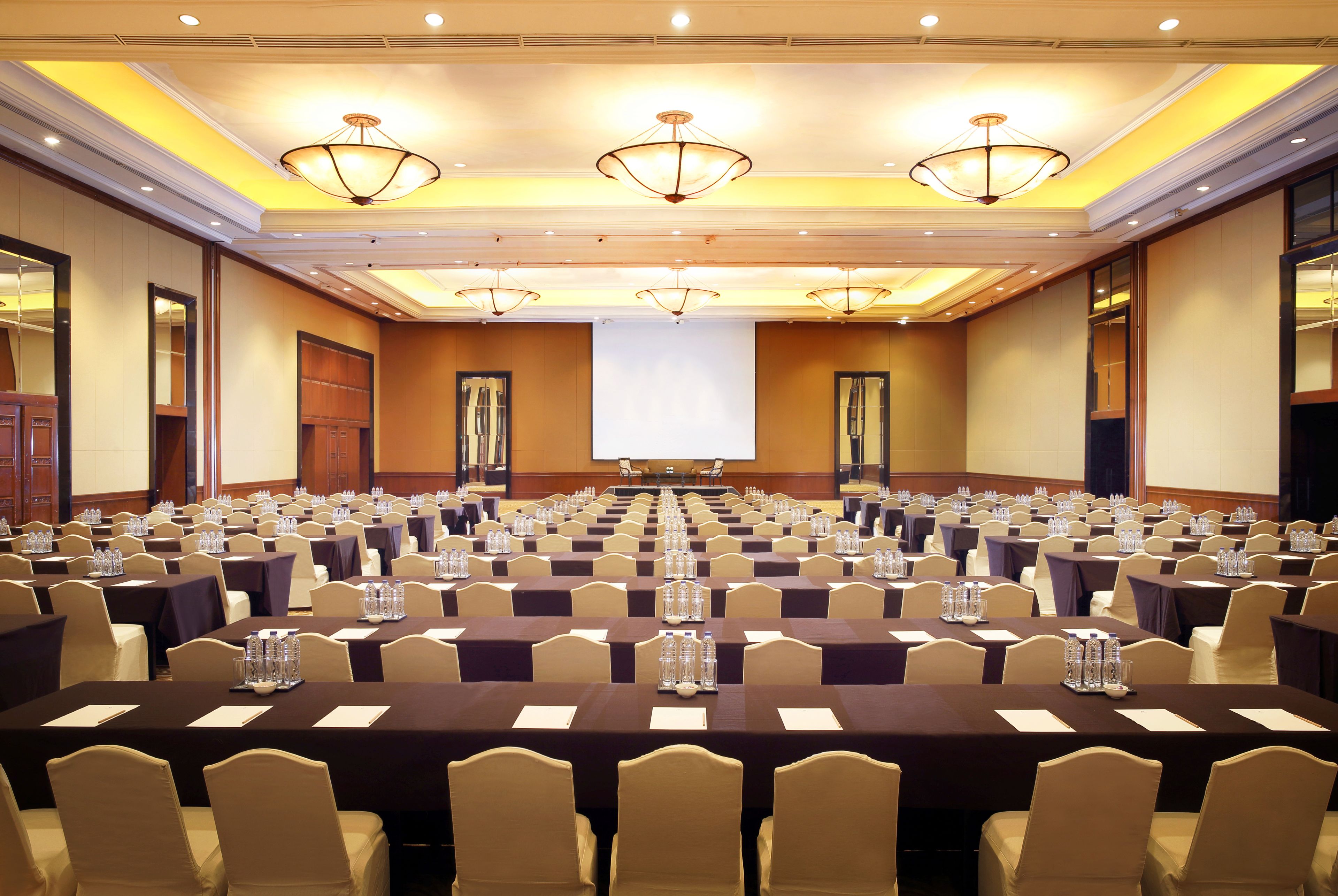 Un salón de conferencias con varias mesas y sillas, equipado con botellas de agua y tarjetas de identificación.