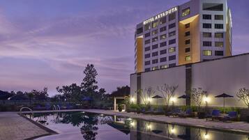 A hotel with a pool area, lounge chairs, and umbrellas.
