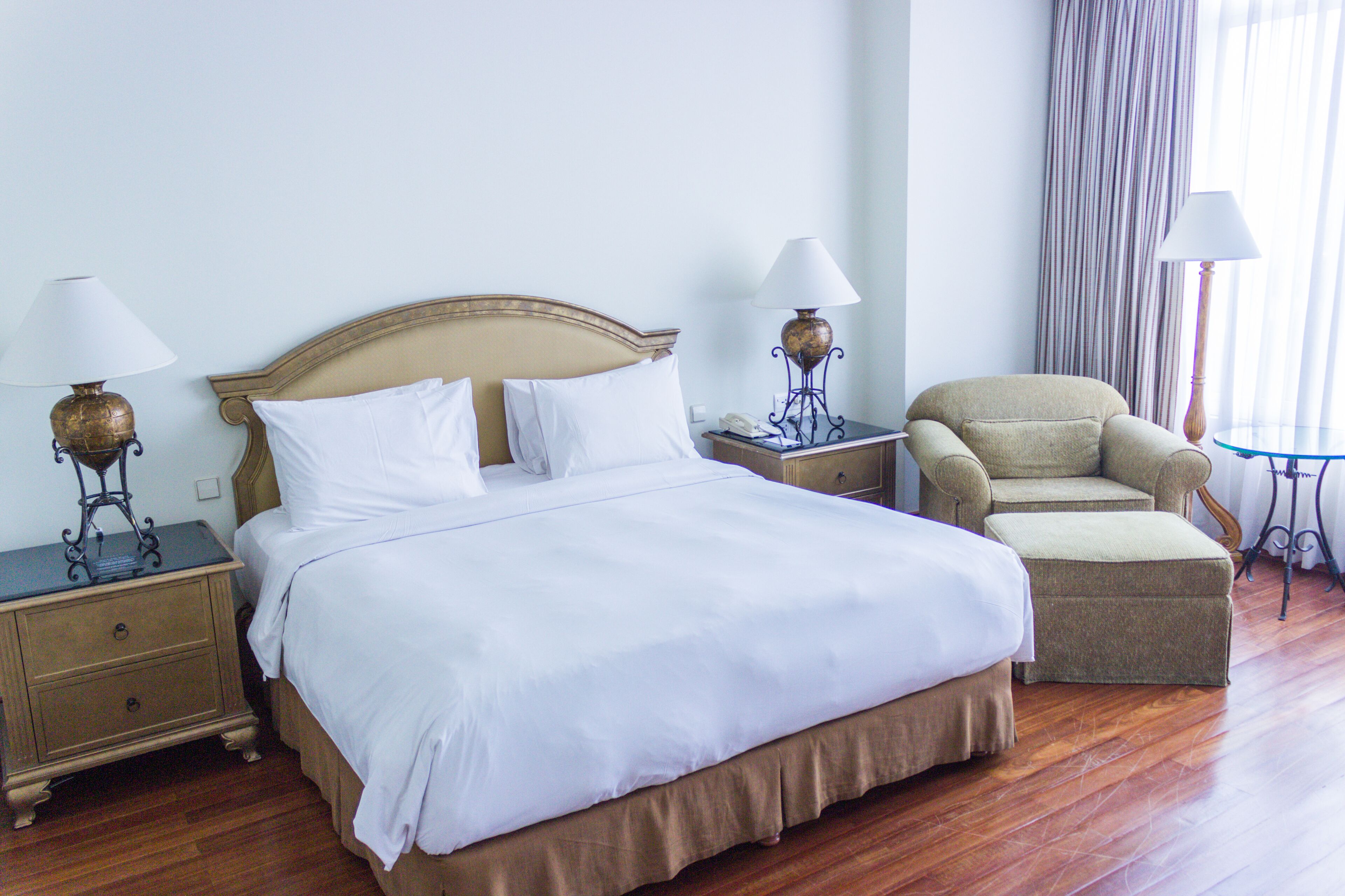 A hotel room with a large bed, two bedside tables with lamps, a chair, and a small table.