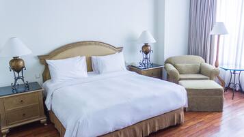 A hotel room with a large bed, two bedside tables with lamps, a chair, and a small table.