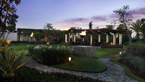 A garden with a stone fountain, a pergola with torches, and a well-maintained lawn. - Aryaduta Bandung (Bandung)