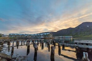 A waterfront property with wooden piers extending into the water, a backdrop of hills, and a clear sky. - Siglo Hotel (Siglufjordur)