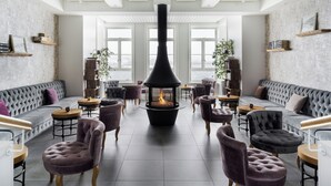 A modern interior with a fireplace, plush seating, and large windows. - Siglo Hotel (Siglufjordur)