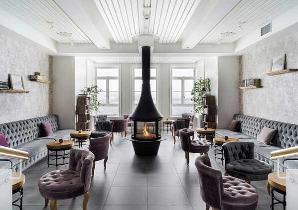 Un interior moderno con chimenea, asientos confortables y ventanas amplias.