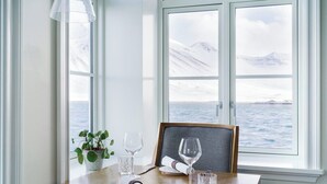 A dining table set with a plant, wine glasses, and a framed picture. - Siglo Hotel (Siglufjordur)
