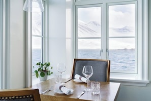 A dining table set with a plant, wine glasses, and a framed picture. - Siglo Hotel (Siglufjordur)