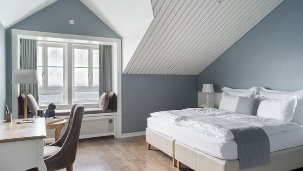 A bedroom with a bed, a desk, and a chair. - Siglo Hotel (Siglufjordur)