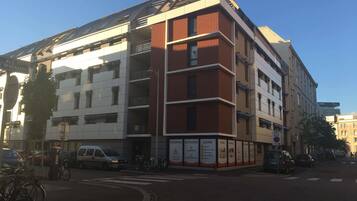 Un edificio de varios pisos con fachadas de ladrillo blanco y rojo, que cuenta con un espacio comercial en la planta baja con letreros que indican 'RESIDENCE', 'HOTELIERIE' y 'LOUISE'.