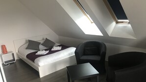 A modern bedroom with a bed, a chair, a small table, and a skylight. - Résidence Hôteliere Louise (Strasbourg)