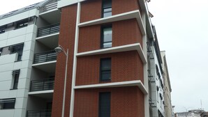 A multi-story building with a modern architectural design, featuring a combination of brick and white exterior walls, large windows, and balconies. - Résidence Hôteliere Louise (Strasbourg)