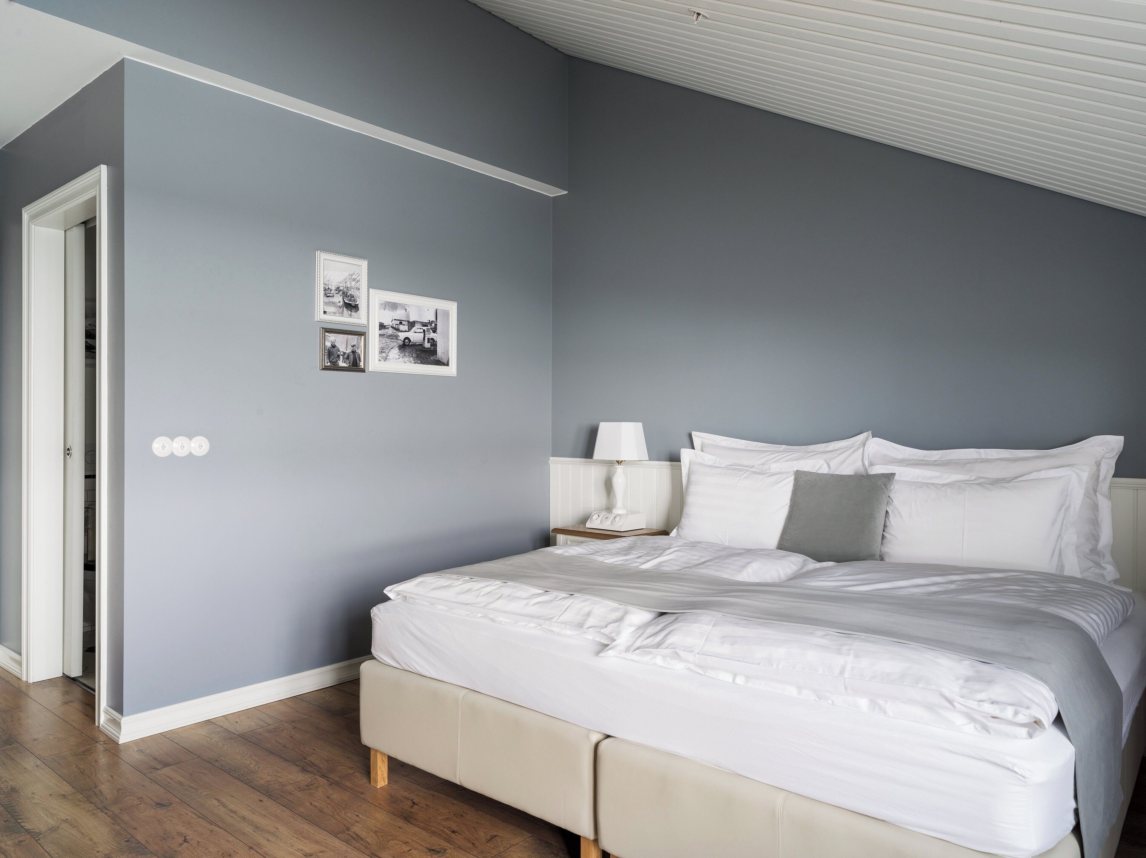 A bedroom with a bed, a nightstand, and a wall-mounted lamp.