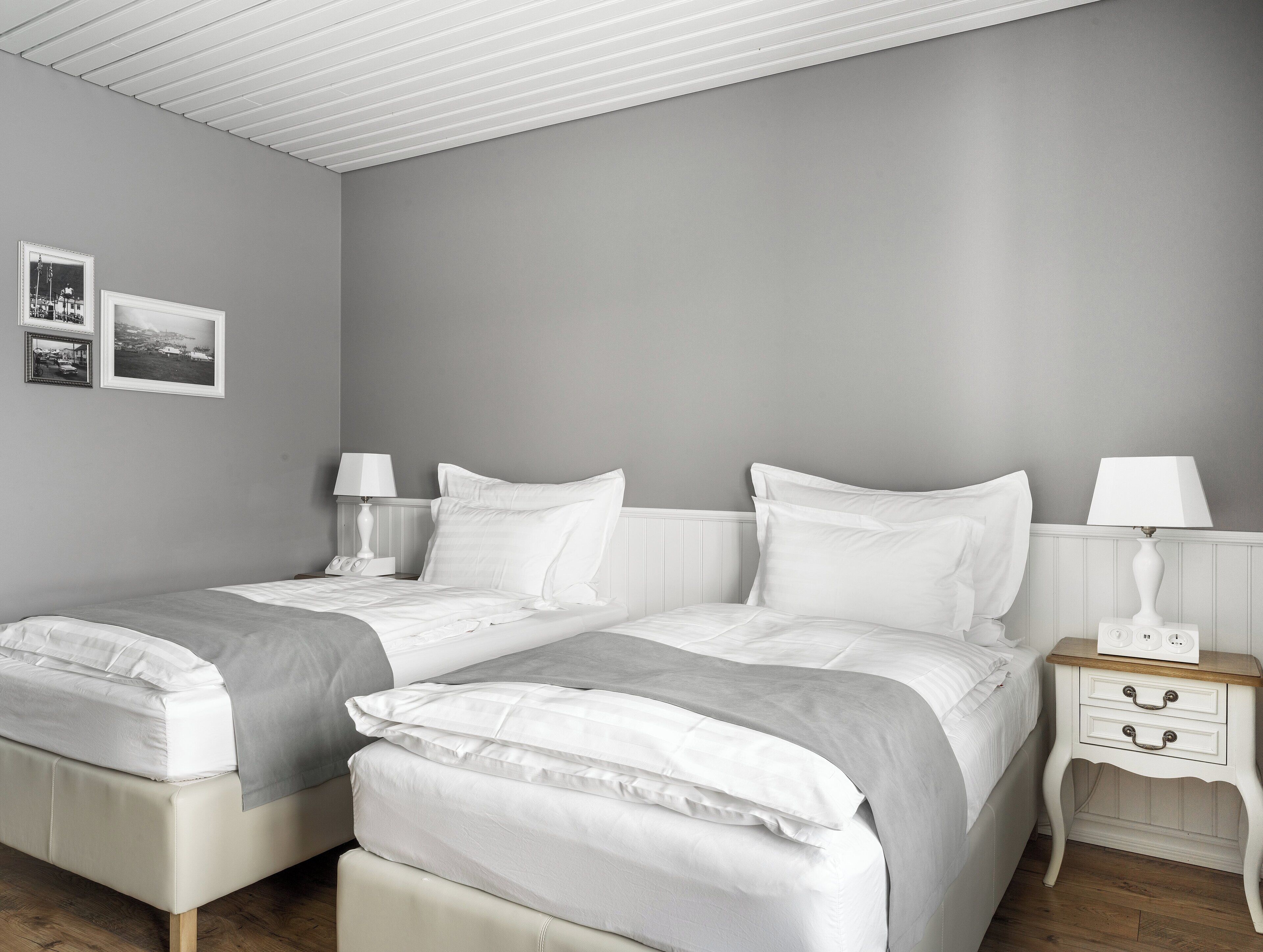 Un dormitorio con dos camas, ropa de cama blanca y mesitas de noche con lámparas.