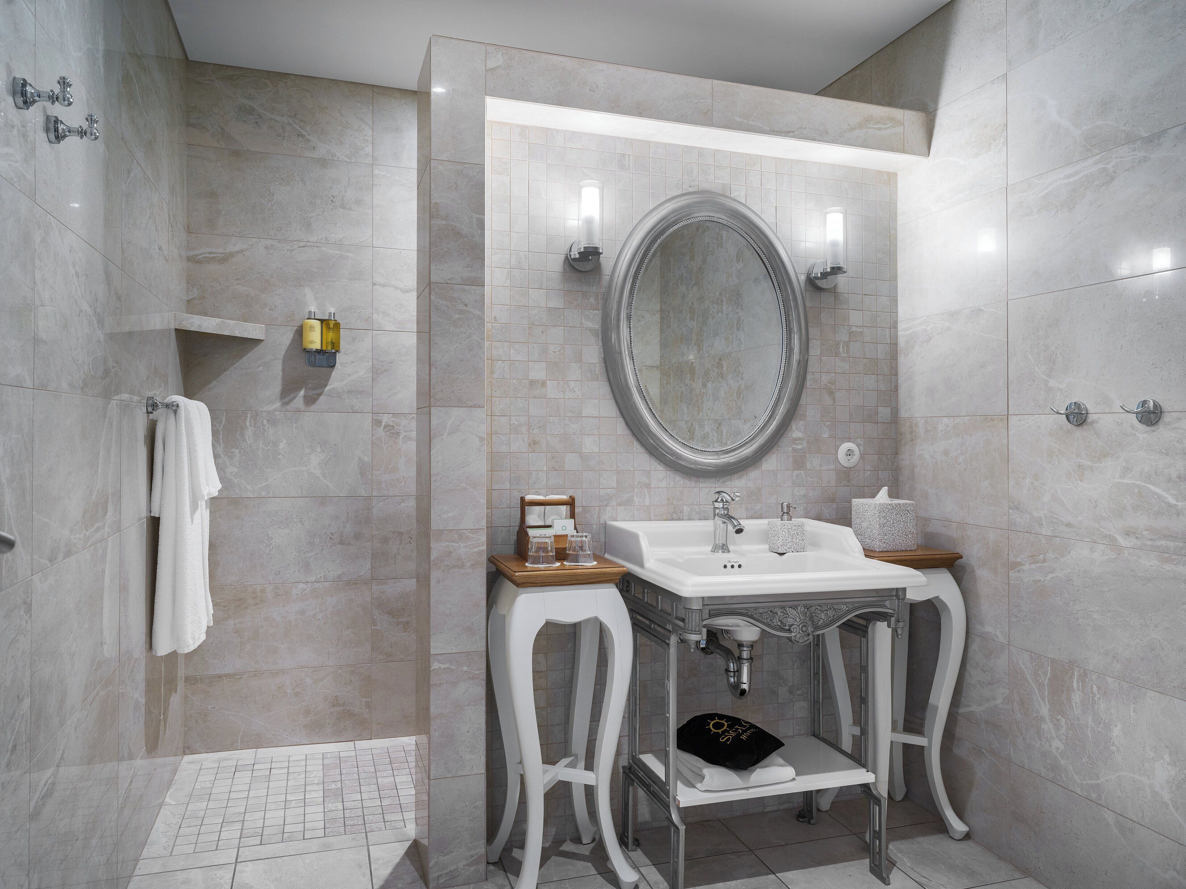 Un baño moderno con un espejo grande, un lavabo y una zona de ducha.
