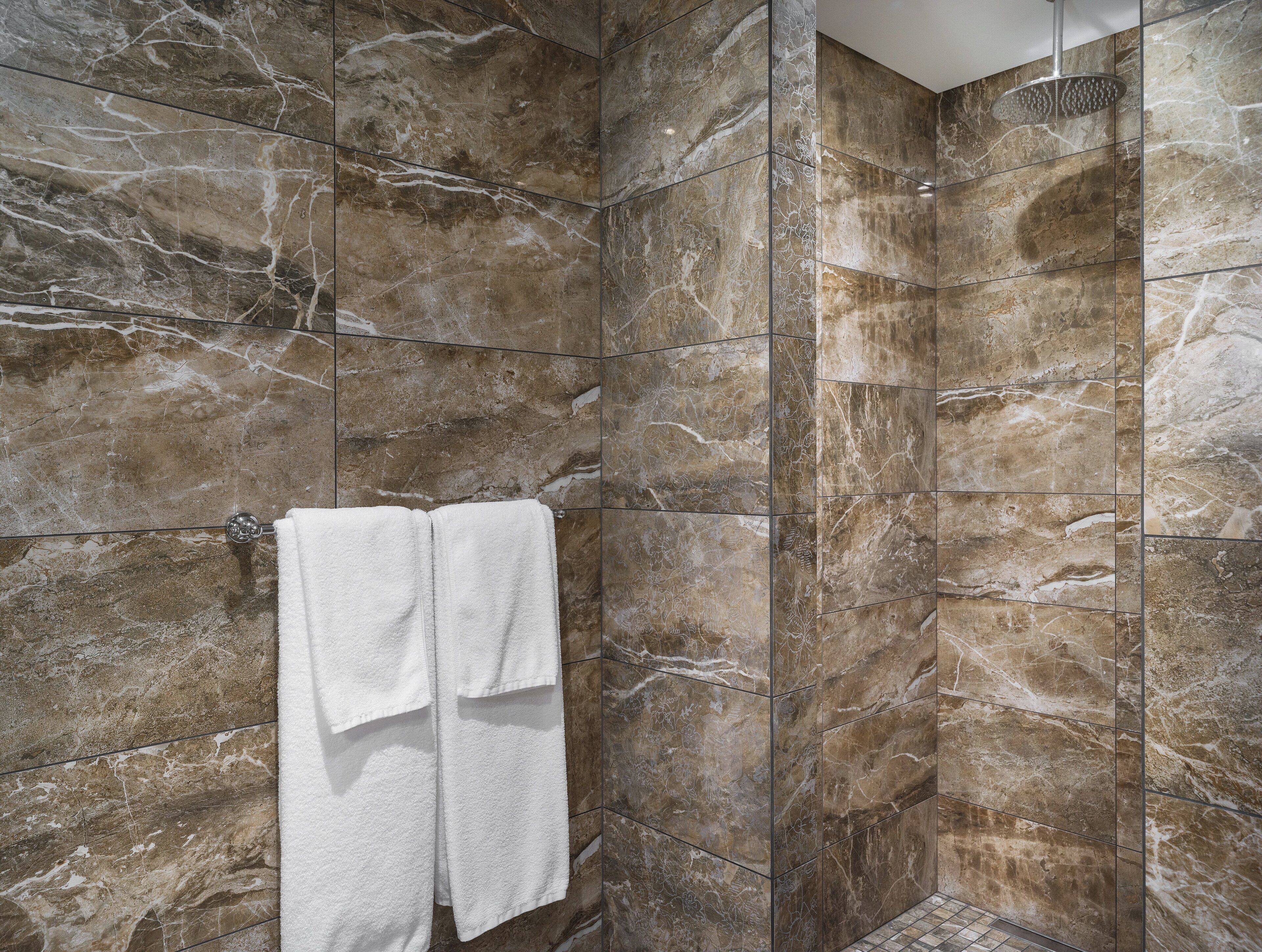 A bathroom with marble walls and a shower area.
