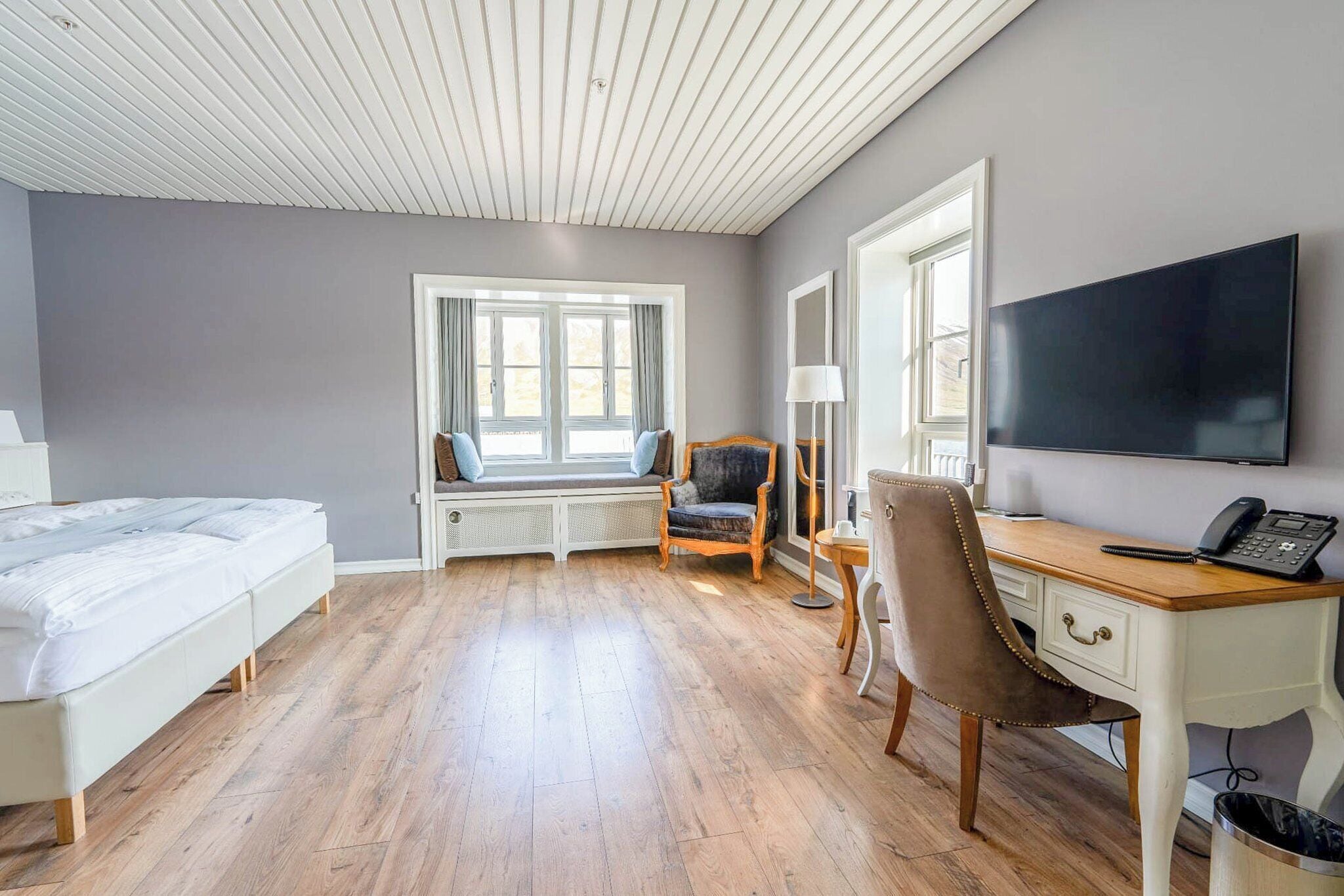 Habitación de hotel con cama, escritorio, silla, televisor y ventana con vistas.
