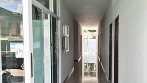 A long, narrow hallway with glass doors on one side and a view of the sky through the ceiling. - Baan Samrarn (Krabi)