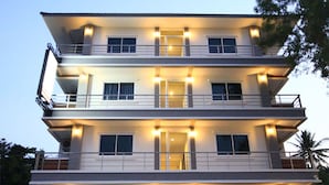Un hotel de varios pisos con un diseño moderno, que cuenta con balcones en cada planta y una entrada de vidrio.
