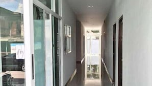 Un pasillo largo y estrecho con puertas de vidrio en un lado y vistas al cielo a través del techo.