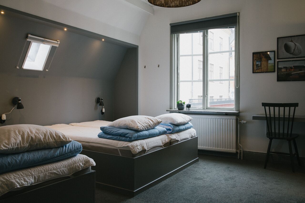 A bedroom with a bed, a desk, a chair, a window, and a radiator.