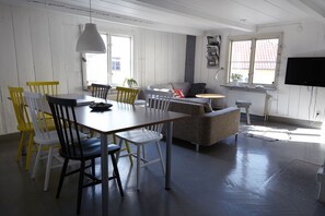 Un coin repas avec une table et des chaises en bois, un canapé et un téléviseur fixé au mur.