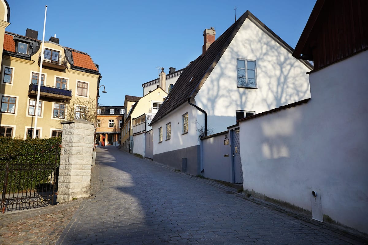 Een geplaveid straatje omzoomd door traditionele gebouwen in Europese stijl, met balkons en een mix van bouwstijlen.