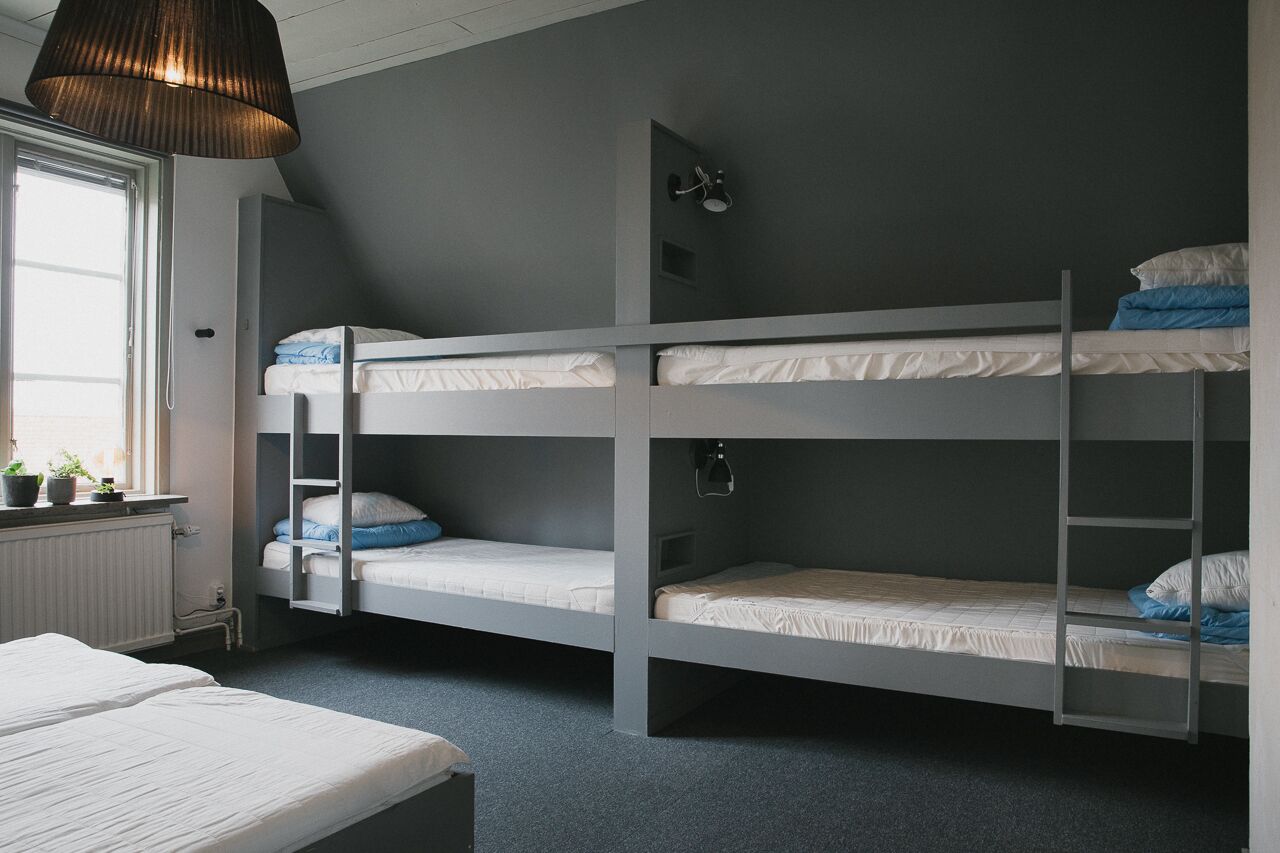 A bunk bed room with a window, radiator, and a hanging light fixture.