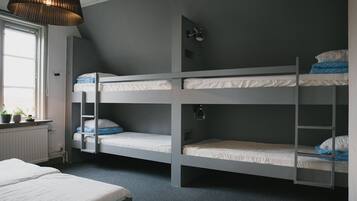 A bunk bed room with a window, radiator, and a hanging light fixture.