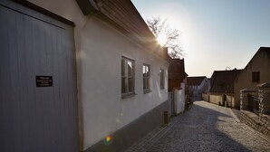 En kullerstensgata med en vit byggnad som har en skylt, en trädörr och ett fönster.