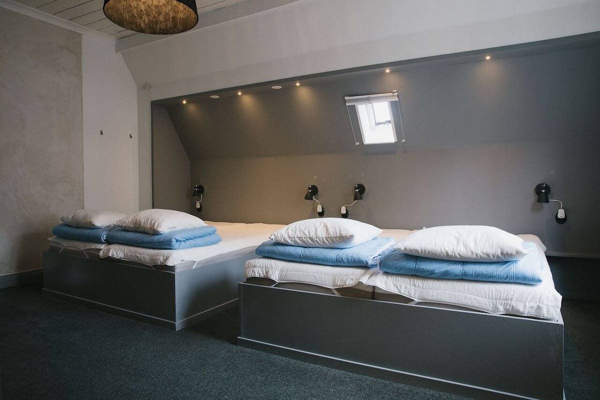 Een moderne hotelkamer met twee enkele bedden, elk met een kussen en een deken.