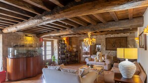 A rustic living room with exposed wooden beams, a glass fish tank, and a cozy seating area with sofas and a coffee table. - Hotel Restaurante Asador de Roxos Casa de Albardonedo (Santiago de Compostela)