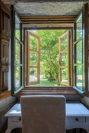 Une pièce avec un bureau et une fenêtre ouverte donnant sur un jardin.