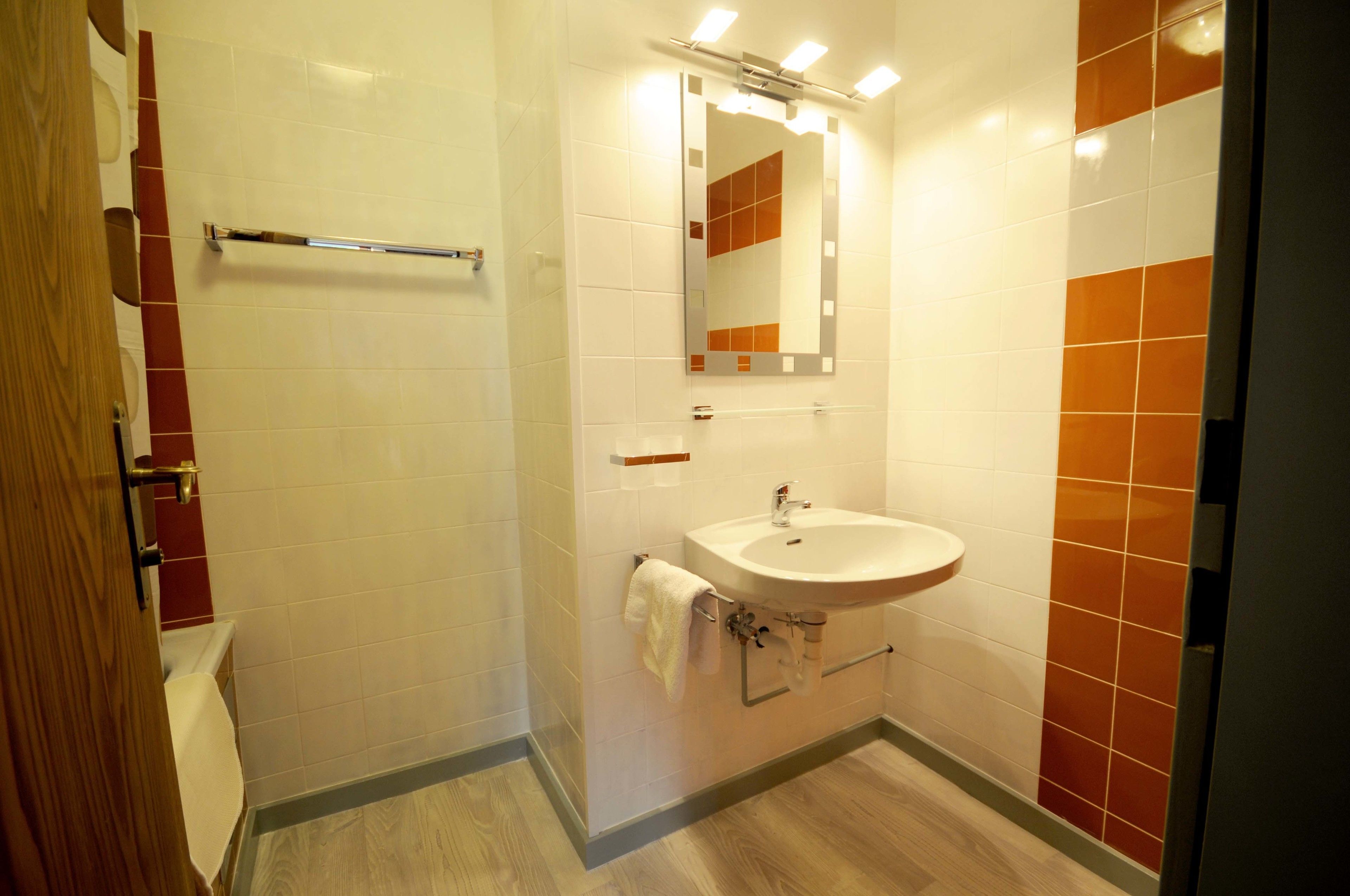 Un baño con lavamanos blanco, espejo y perchero.
