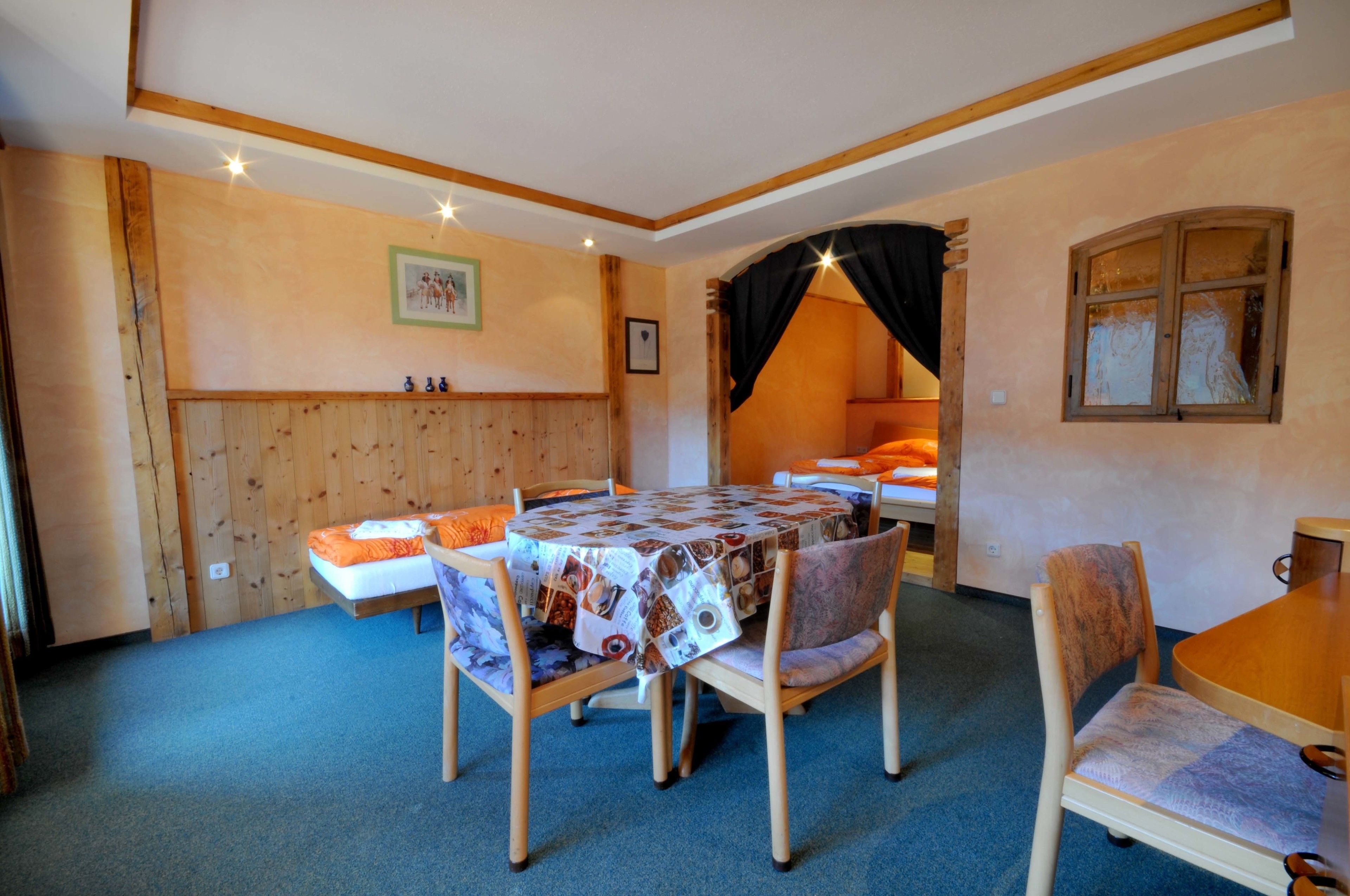 Una habitación acogedora con una cama de madera, una mesa redonda con sillas y un ventanal.