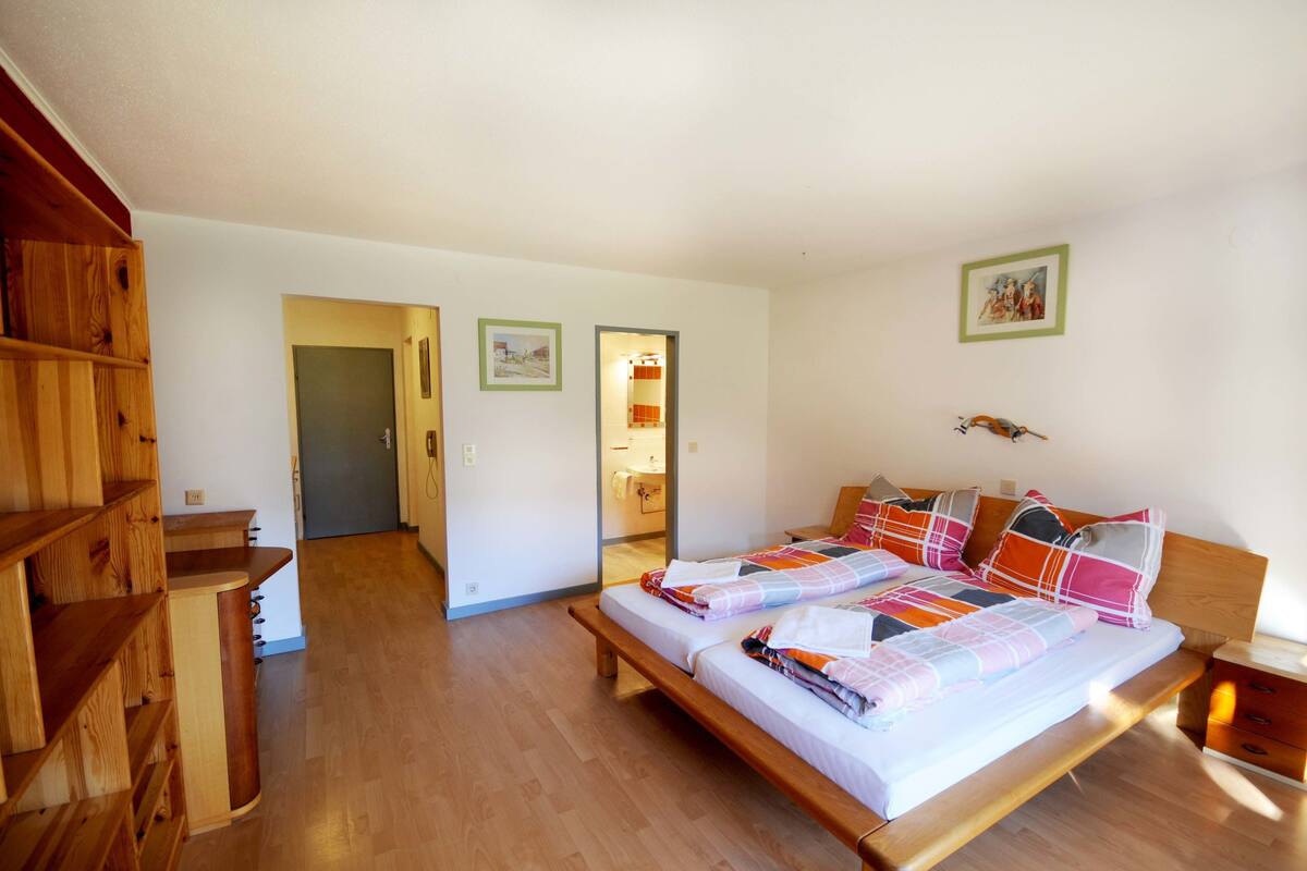 Un dormitorio con una cama de madera, un banco de madera y una estantería de madera.