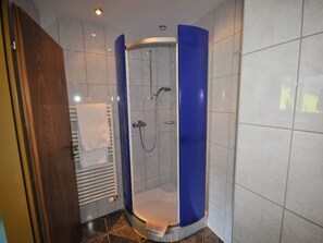 Una ducha con diseño curvo, pared de azulejos blancos y una pared de acento azul.