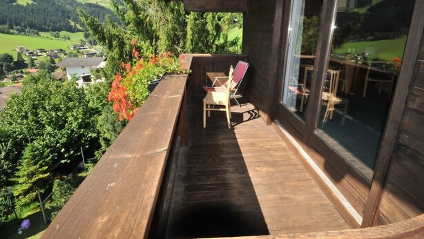 A wooden deck with a view of a valley and mountains.