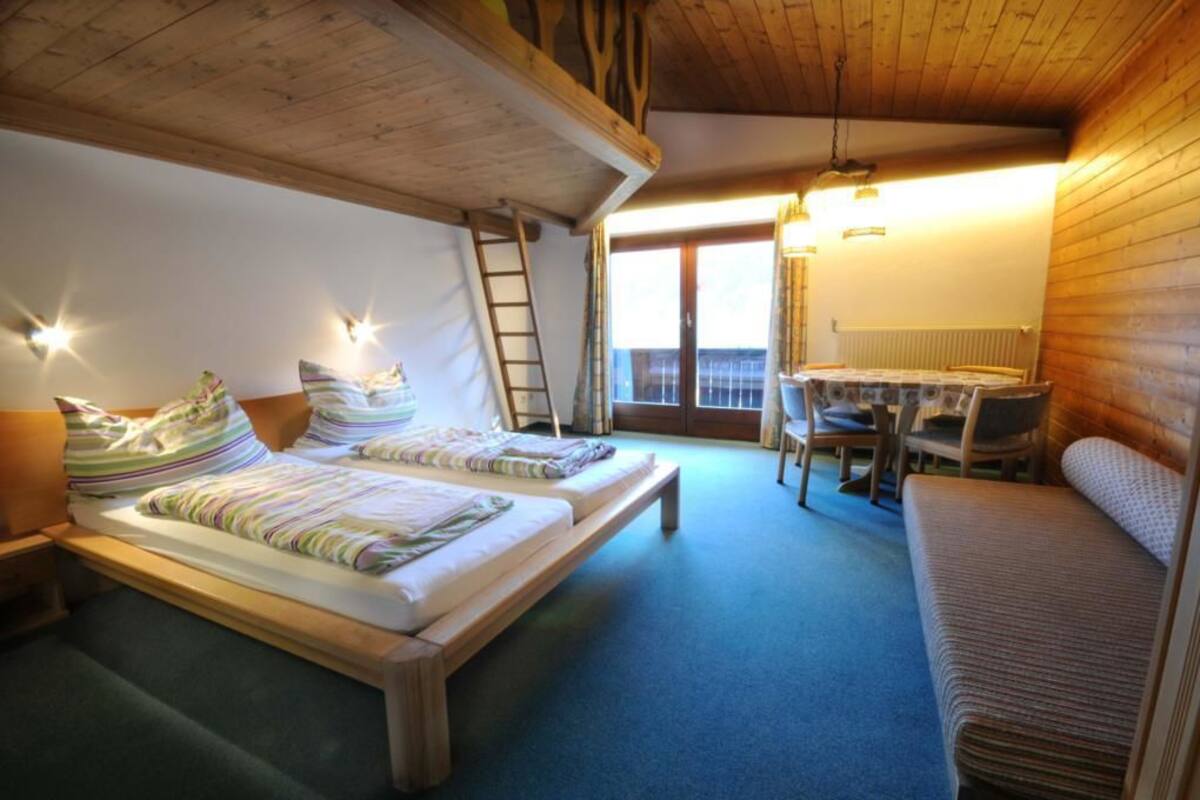 Una habitación acogedora con dos camas, techo de madera, escritorio con silla y vista por una ventana grande.