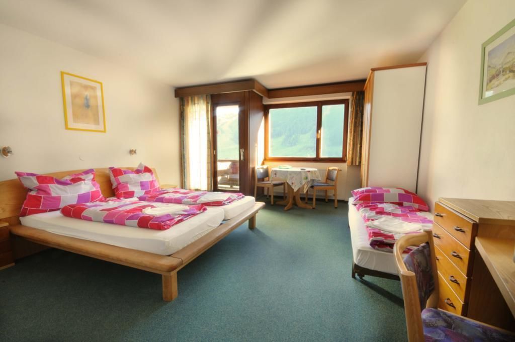 Een slaapkamer met een bed, een stoel, een dressoir en een raam met uitzicht op de omgeving.