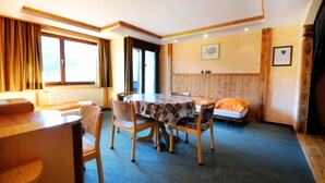 A cozy room with a round table, chairs, a sofa, and a bed.