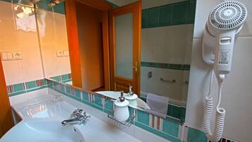 A bathroom with a large sink, a mirror, a hairdryer, and a towel rack.