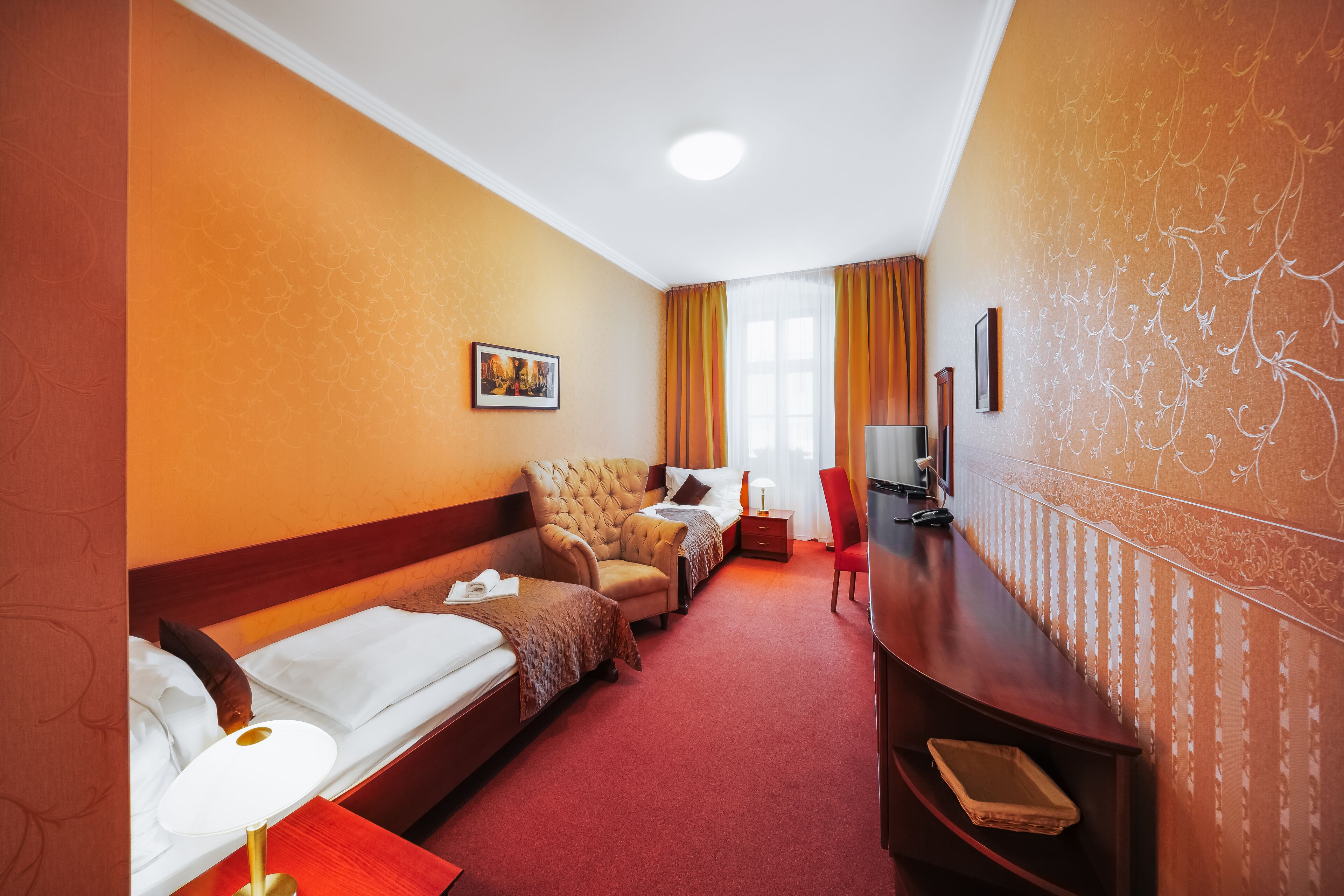 Una habitación de hotel con dos camas individuales, un sofá, un televisor y un escritorio.