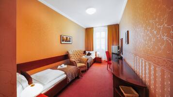Una habitación de hotel con dos camas individuales, un sofá, un televisor y un escritorio.