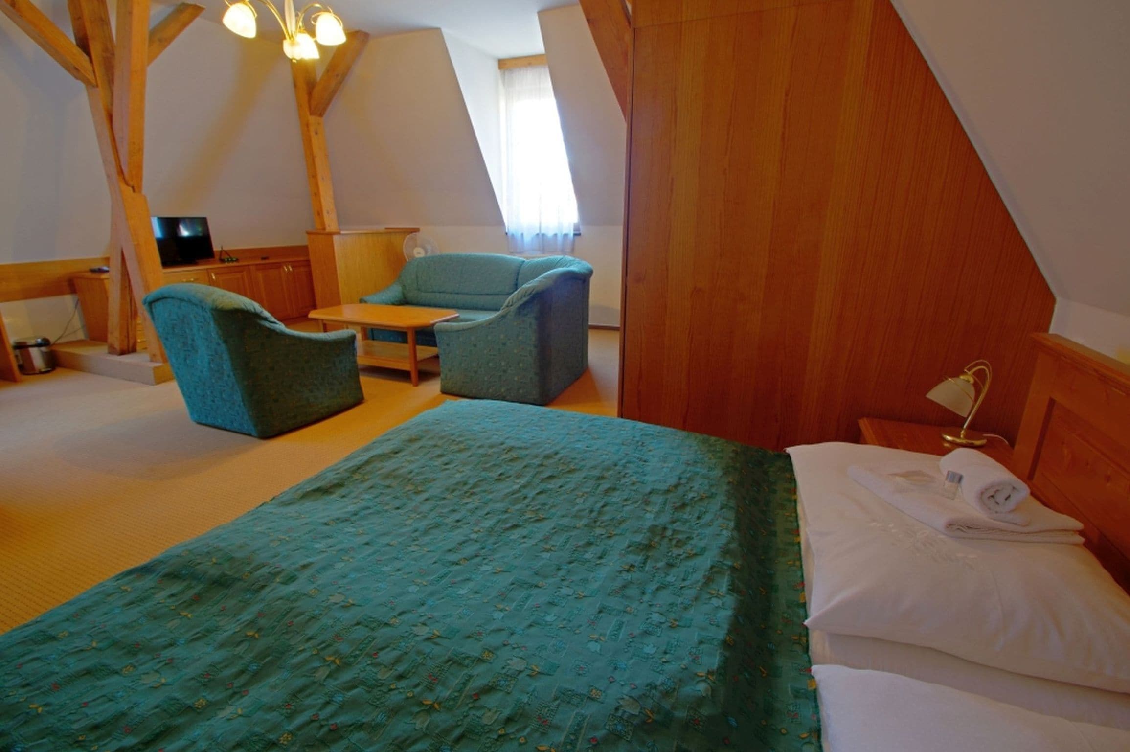Una habitación acogedora con una cama, un sofá, una mesita y un televisor.