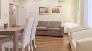 Una sala de estar moderna con un sofá, sillas, una mesa de comedor y cuadros en la pared.