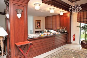 Une cuisine avec des meubles en bois, un bar pour prendre le petit-déjeuner et un lustre.