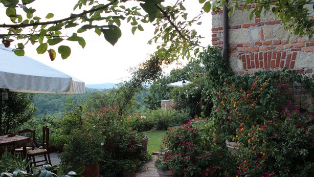 Un jardín con plantas en macetas, un camino de ladrillo y una mesa con sillas.