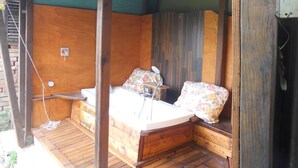 Una cabaña de madera con jacuzzi integrado, una terraza de madera y un ventanal.