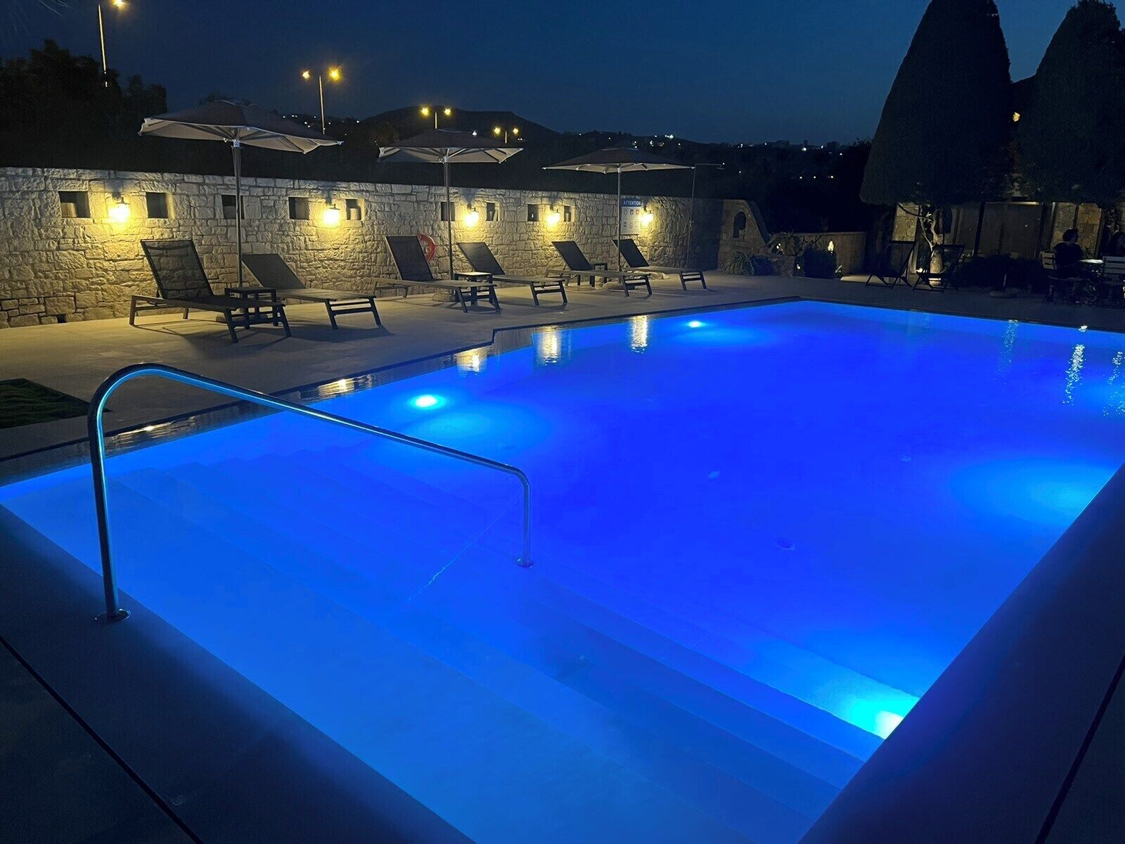 Ein Pool mit blauem Licht, Steinwänden und Liegestühlen.