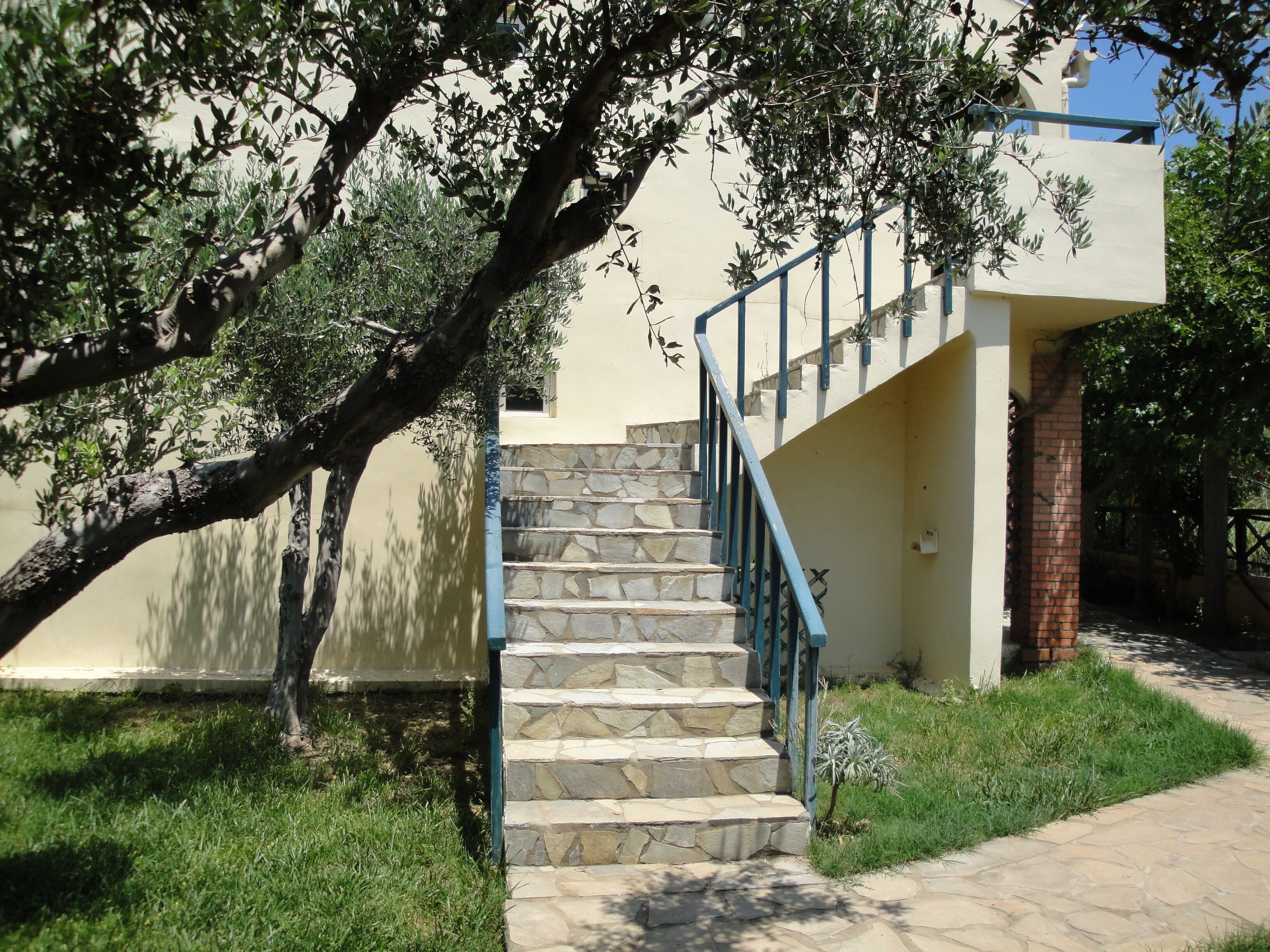 Una escalera de piedra con barandales azules que conduce a un edificio de fachada color beige.