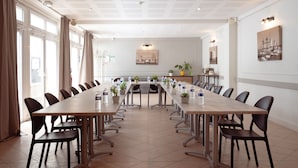 A conference room with a long table, chairs, potted plants, and a painting on the wall. - Hôtel Le Rivage (Chatelaillon-Plage)